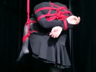 Student girl hanging by one leg and bound up.